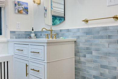 Mid-sized trendy master blue tile and ceramic tile ceramic tile, brown floor, single-sink and wainscoting bathroom photo in DC Metro with shaker cabinets, white cabinets, a two-piece toilet, white walls, a drop-in sink, marble countertops, white countertops, a niche and a built-in vanity