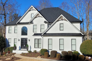 Large arts and crafts white two-story stucco exterior home photo in Atlanta with a shingle roof and a gray roof