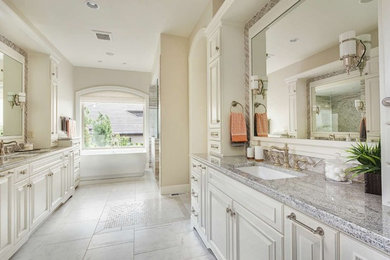 Example of a large classic master marble floor and white floor bathroom design in St Louis with raised-panel cabinets, white cabinets, beige walls, an undermount sink, quartz countertops and a hinged shower door