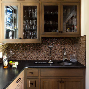 Cette image montre une très grande arrière-cuisine rustique avec un évier intégré, un placard à porte plane, des portes de placard en bois brun, un plan de travail en onyx, une crédence en carreau de verre, un électroménager encastrable, un sol en bois brun, aucun îlot et un plan de travail noir.