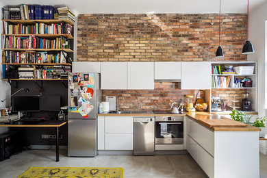 Example of a small urban l-shaped concrete floor kitchen design in Other with flat-panel cabinets, white cabinets, wood countertops, red backsplash, stainless steel appliances and a peninsula