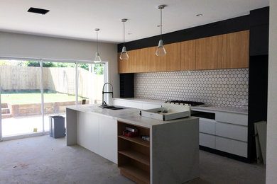 This is an example of a mid-sized contemporary galley open plan kitchen in Brisbane with marble benchtops, white splashback, ceramic splashback and with island.