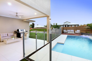 Mid-sized modern side yard custom-shaped aboveground pool in Cairns with a hot tub and decking.