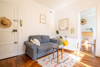 Réalisation d'un salon design fermé avec un mur blanc, un sol en bois brun, aucune cheminée et un sol marron.