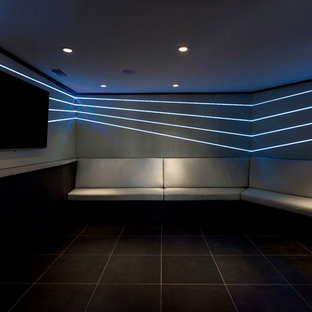 Cette image montre une petite salle de cinéma design fermée avec un sol en marbre, un mur gris, un téléviseur fixé au mur et un sol noir.