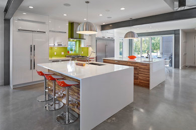 Mid-sized trendy concrete floor and gray floor kitchen photo in Edmonton with an undermount sink, flat-panel cabinets, quartz countertops, green backsplash, glass sheet backsplash, two islands, white countertops, white cabinets and stainless steel appliances