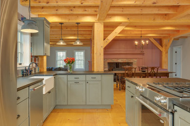 Eat-in kitchen - large rustic l-shaped light wood floor, yellow floor and exposed beam eat-in kitchen idea in Boston with a farmhouse sink, shaker cabinets, black cabinets, soapstone countertops, multicolored backsplash, ceramic backsplash, stainless steel appliances, an island and black countertops