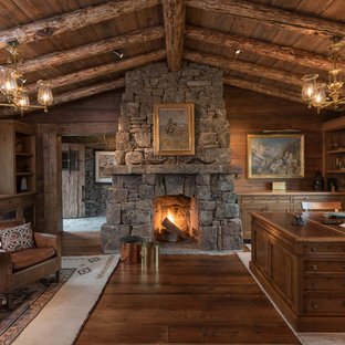 This is an example of a rustic study in Other with medium hardwood flooring, a standard fireplace, a stone fireplace surround and a freestanding desk.
