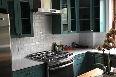 Mid-sized transitional u-shaped dark wood floor and gray floor enclosed kitchen photo in Detroit with shaker cabinets, blue cabinets, solid surface countertops, white backsplash, stainless steel appliances, an island, a farmhouse sink and subway tile backsplash