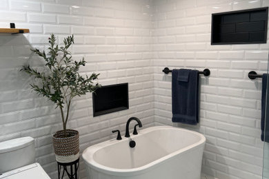 Inspiration for a large modern master white tile and ceramic tile porcelain tile and white floor freestanding bathtub remodel in Other with a bidet, white walls and a niche