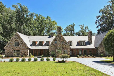 Example of a large mountain style brown three-story stone exterior home design in DC Metro with a clipped gable roof