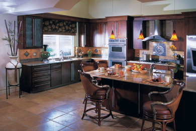Eat-in kitchen - mid-sized zen l-shaped travertine floor eat-in kitchen idea in New York with a double-bowl sink, flat-panel cabinets, dark wood cabinets, granite countertops, beige backsplash, stone tile backsplash, stainless steel appliances and an island