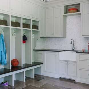 Large classic l-shaped separated utility room in Chicago with white walls, marble flooring, a belfast sink, recessed-panel cabinets, composite countertops, a concealed washer and dryer and grey cabinets.