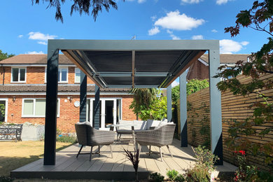 This is an example of a medium sized modern back partial sun pergola in Other with decking.