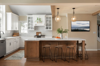 Inspiration for a large transitional l-shaped medium tone wood floor, brown floor and vaulted ceiling eat-in kitchen remodel in Milwaukee with an undermount sink, shaker cabinets, medium tone wood cabinets, quartz countertops, white backsplash, subway tile backsplash, stainless steel appliances, an island and white countertops