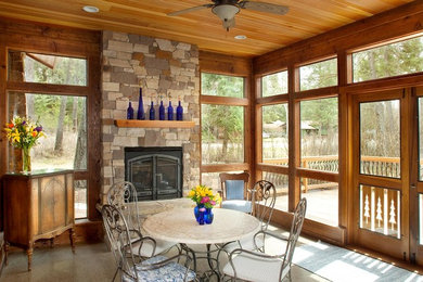 Mountain style concrete floor sunroom photo in Other with a standard ceiling and a stone fireplace