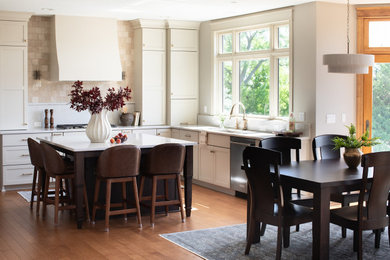 Eat-in kitchen - large transitional medium tone wood floor and brown floor eat-in kitchen idea in Other with an undermount sink, shaker cabinets, white cabinets, quartz countertops, beige backsplash, porcelain backsplash, stainless steel appliances, an island and white countertops