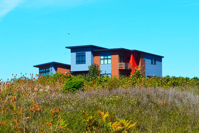 Inspiration for a mid-sized contemporary red two-story mixed siding house exterior remodel in Seattle with a shed roof and a metal roof