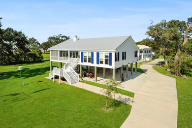 Diseño de fachada de casa blanca y gris costera de dos plantas con revestimiento de aglomerado de cemento, tejado a dos aguas, tejado de metal y tablilla
