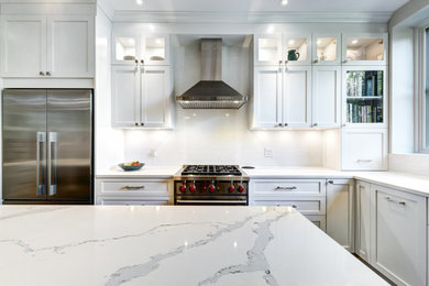 Example of a large trendy dark wood floor kitchen pantry design in Los Angeles with a drop-in sink, recessed-panel cabinets, white cabinets, white backsplash, glass tile backsplash, stainless steel appliances, an island and white countertops