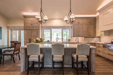 Inspiration for a large eclectic medium tone wood floor and gray floor kitchen remodel in Phoenix with a farmhouse sink, recessed-panel cabinets, medium tone wood cabinets, quartz countertops, gray backsplash, ceramic backsplash, stainless steel appliances, an island and white countertops