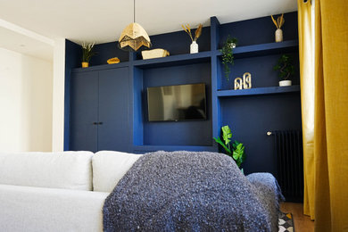 Imagen de biblioteca en casa abierta contemporánea de tamaño medio sin chimenea con paredes azules, suelo de madera clara, pared multimedia y suelo beige
