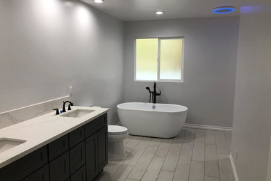 Bathroom - large modern master ceramic tile and gray floor bathroom idea in Los Angeles with a two-piece toilet, gray walls, quartz countertops, a hinged shower door and white countertops