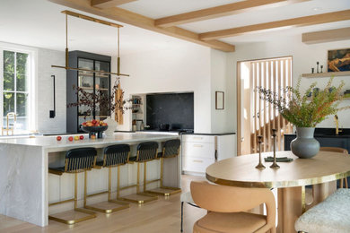 Danish light wood floor kitchen photo in Minneapolis with a farmhouse sink, flat-panel cabinets, quartzite countertops, white backsplash, ceramic backsplash, paneled appliances, an island and gray countertops