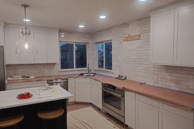 Large trendy u-shaped light wood floor open concept kitchen photo in Denver with an undermount sink, shaker cabinets, white cabinets, quartzite countertops, multicolored backsplash, porcelain backsplash, stainless steel appliances, an island and white countertops