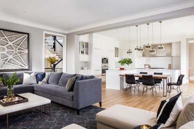 Example of a large transitional l-shaped light wood floor and brown floor open concept kitchen design in Calgary with a farmhouse sink, shaker cabinets, white cabinets, marble countertops, white backsplash, stainless steel appliances, an island and white countertops