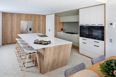Photo of a large modern kitchen in Perth with a double-bowl sink, shaker cabinets, quartz benchtops, green splashback, glass sheet splashback, black appliances, porcelain floors and with island.