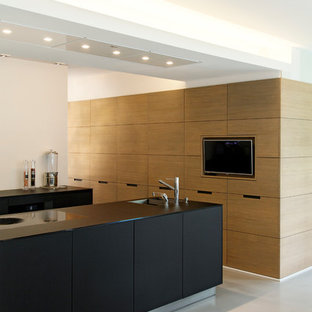 Modelo de cocina moderna, de tamaño medio, abierta, con fregadero de un seno, armarios con paneles lisos, puertas de armario de madera clara y una isla