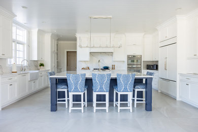 Example of a classic u-shaped shiplap ceiling and gray floor kitchen design in New York with an island, a farmhouse sink, white cabinets, marble countertops, marble backsplash, stainless steel appliances, white countertops, recessed-panel cabinets and white backsplash