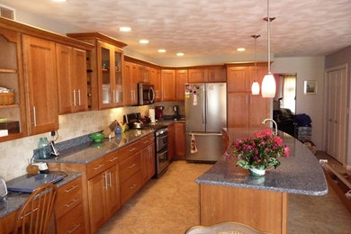 Eat-in kitchen - mid-sized traditional l-shaped travertine floor and beige floor eat-in kitchen idea in Chicago with recessed-panel cabinets, medium tone wood cabinets, granite countertops, beige backsplash, stone tile backsplash, stainless steel appliances and an island