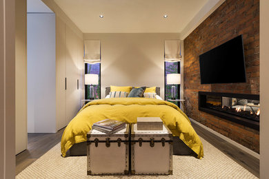 Inspiration for a mid-sized contemporary master bedroom in Melbourne with white walls, medium hardwood floors, brown floor, a two-sided fireplace, a metal fireplace surround and brick walls.