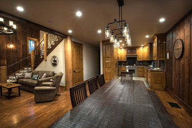 Large mountain style medium tone wood floor and brown floor great room photo in Other with beige walls and no fireplace