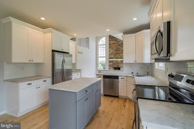 Example of a mid-sized transitional l-shaped light wood floor and brown floor eat-in kitchen design in Philadelphia with an undermount sink, shaker cabinets, white cabinets, quartzite countertops, white backsplash, subway tile backsplash, stainless steel appliances, an island and white countertops