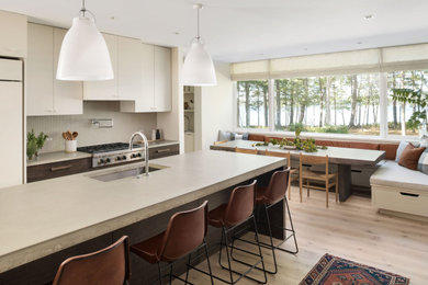 Inspiration for a large contemporary galley light wood floor and brown floor eat-in kitchen remodel in Portland Maine with an undermount sink, flat-panel cabinets, concrete countertops, gray backsplash, ceramic backsplash, paneled appliances, an island and gray countertops
