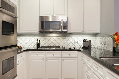 Mid-sized elegant u-shaped medium tone wood floor enclosed kitchen photo in Chicago with an undermount sink, shaker cabinets, white cabinets, granite countertops, white backsplash, ceramic backsplash, stainless steel appliances and no island