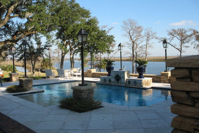 This is an example of a mid-sized traditional backyard custom-shaped lap pool in New Orleans with a water feature and concrete pavers.
