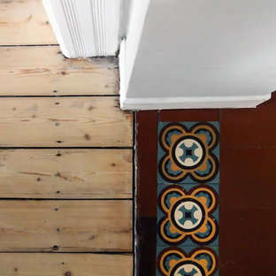 Klassisk inredning av en mellanstor hall, med grå väggar, klinkergolv i keramik och rött golv