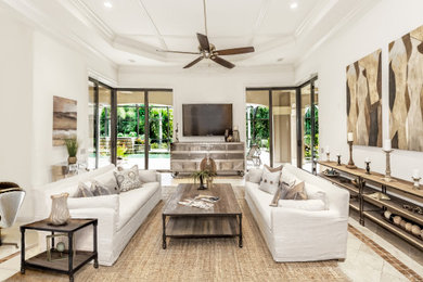 Large trendy open concept travertine floor and beige floor family room photo in Tampa with beige walls and a tv stand