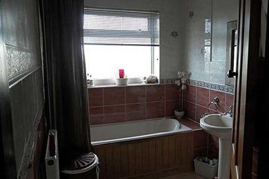 Foto på ett funkis badrum för barn, med en dusch/badkar-kombination, en toalettstol med hel cisternkåpa, beige kakel, keramikplattor, linoleumgolv, ett väggmonterat handfat, brunt golv och ett platsbyggt badkar