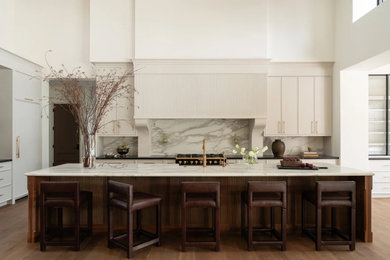 Kitchen - huge transitional l-shaped vaulted ceiling, medium tone wood floor and brown floor kitchen idea in Denver with white cabinets, marble countertops, marble backsplash, paneled appliances, an island, a farmhouse sink, recessed-panel cabinets, gray backsplash and gray countertops