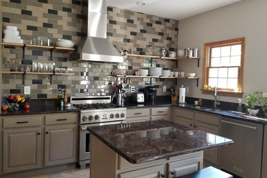 Mid-sized urban l-shaped ceramic tile and beige floor open concept kitchen photo in Other with an undermount sink, raised-panel cabinets, gray cabinets, granite countertops, gray backsplash, ceramic backsplash, stainless steel appliances, an island and black countertops