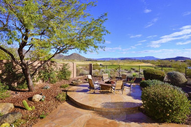This is an example of a large southwestern backyard stone landscaping in Phoenix with a fire pit.