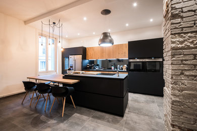 Large contemporary galley open plan kitchen in Lyon with a single-bowl sink, laminate benchtops, grey splashback, mirror splashback, black appliances, ceramic floors, with island and grey floor.