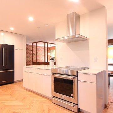 Remodeled White Flat Front Kitchen in Midcentury Home with Exposed Brick