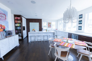 Example of a minimalist u-shaped dark wood floor and brown floor open concept kitchen design in Jacksonville with flat-panel cabinets, dark wood cabinets, paneled appliances, an island and white countertops