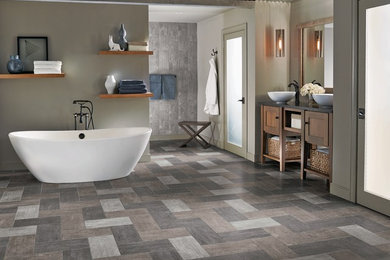 Inspiration for a mid-sized tropical master gray tile and ceramic tile slate floor and gray floor freestanding bathtub remodel in San Diego with shaker cabinets, medium tone wood cabinets, gray walls, a vessel sink and solid surface countertops